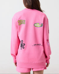 Person wearing a pink Clueless sweatshirt with various logos on the back against a white background