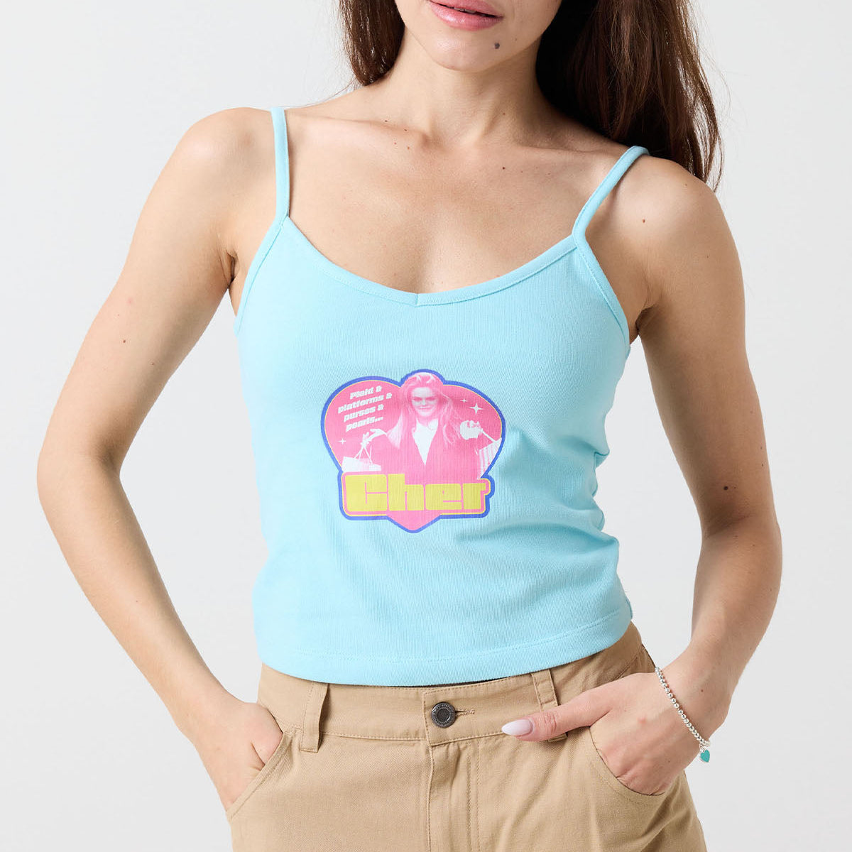Woman wearing a light blue Cher from Clueless tank top with a colorful graphic design on a plain background