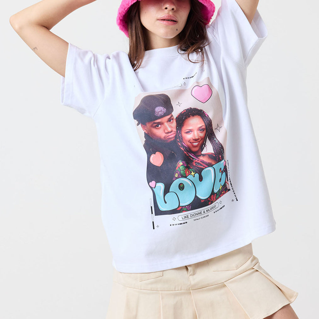 Person wearing a white t-shirt with a graphic design and a pink bucket hat on a plain background