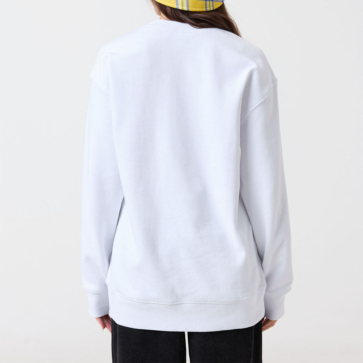 Person wearing a white sweatshirt and yellow checkered hat on a white background