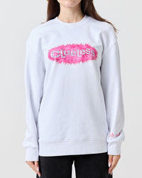 Person wearing a light gray sweatshirt with a pink and white Clueless logo on a plain background