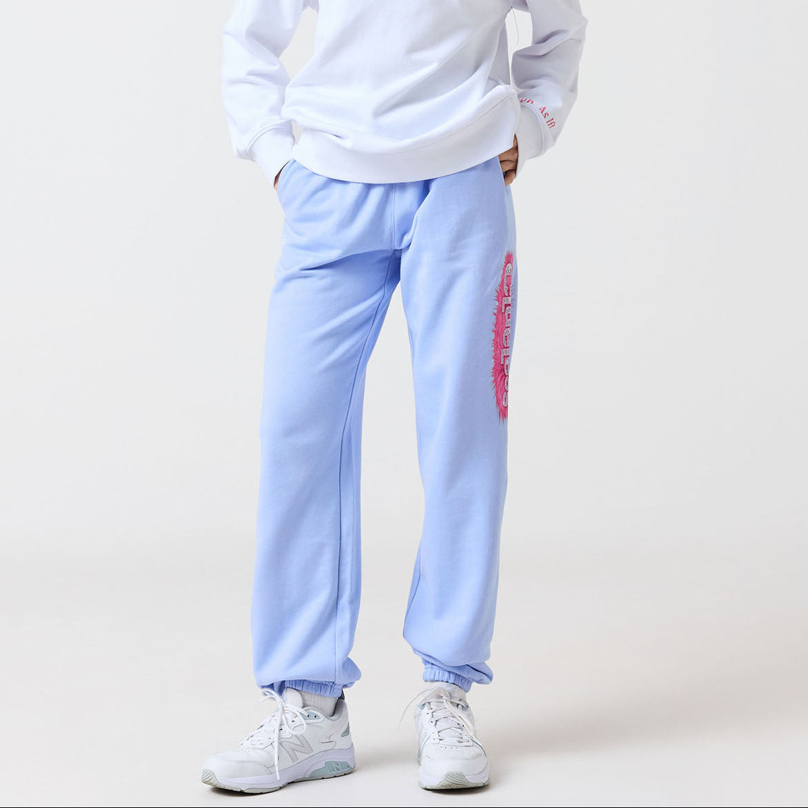 Person wearing a white sweatshirt and light blue pants with a logo on a white background
