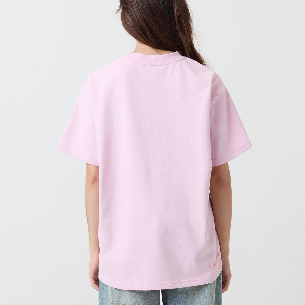 Person wearing a pink t-shirt with a brand logo on a white background