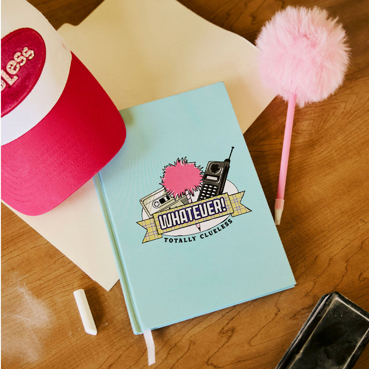 Clueless notebook with a colorful design on a wooden surface with stationery items.