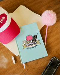 Clueless notebook with a colorful design on a wooden surface with stationery items.