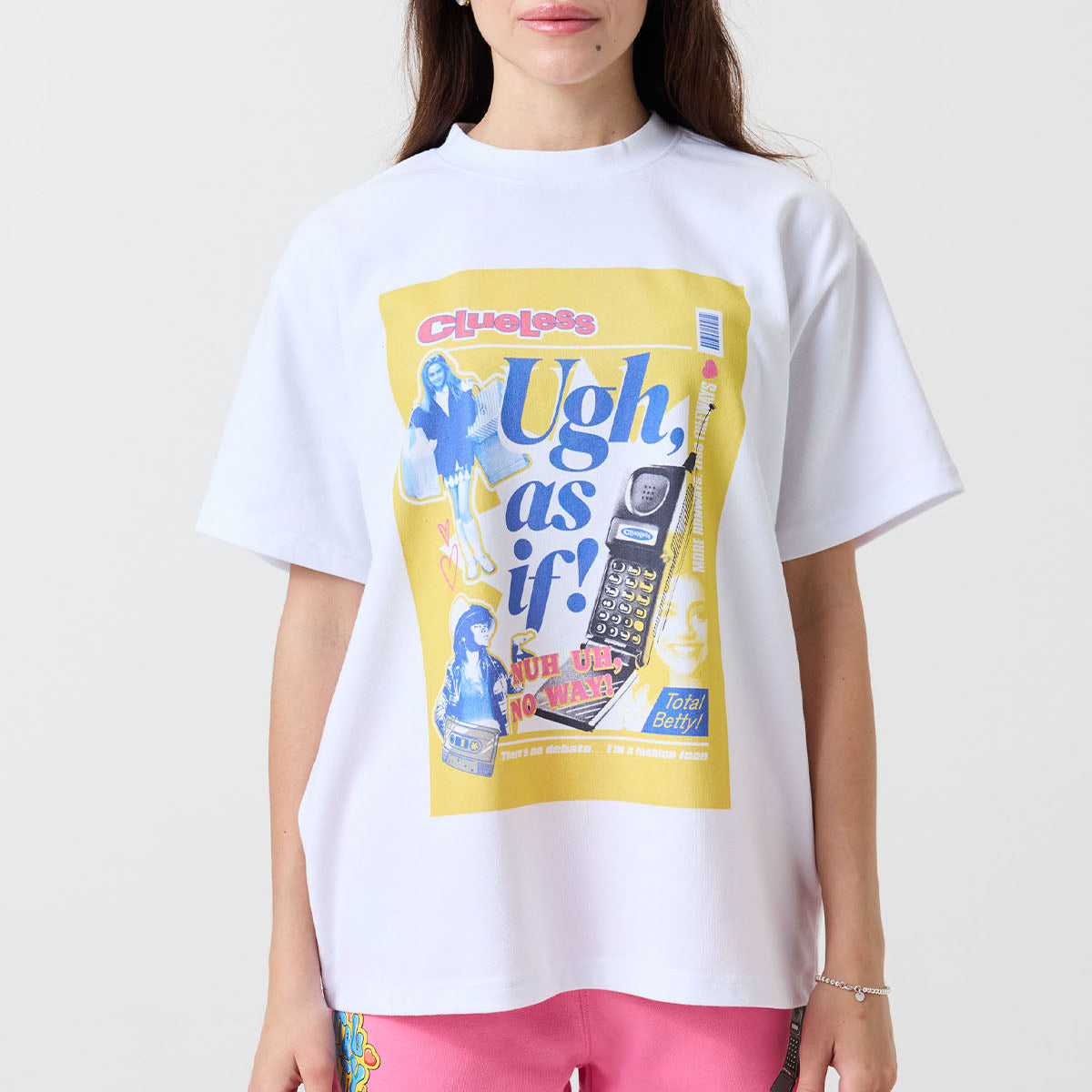 Person wearing a white t-shirt with a colorful graphic design from Clueless on a plain background