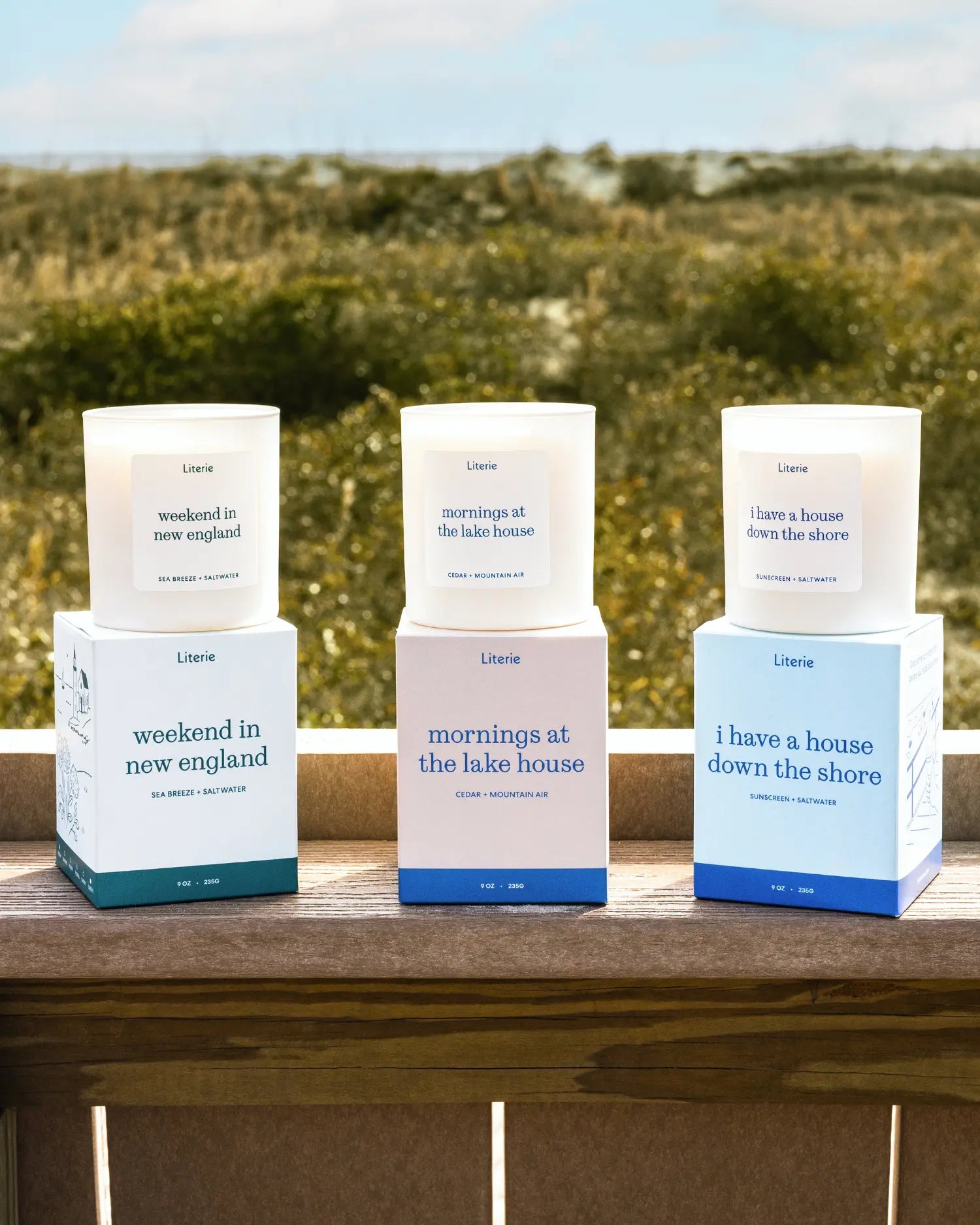 'weekend in new england', 'mornings at the lake house', and 'i have a house down the shore' candles lined up at the beach.