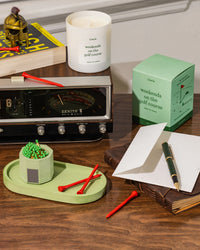Golf-themed items including a candle by Literie, green candle tray and match holder on a desk.