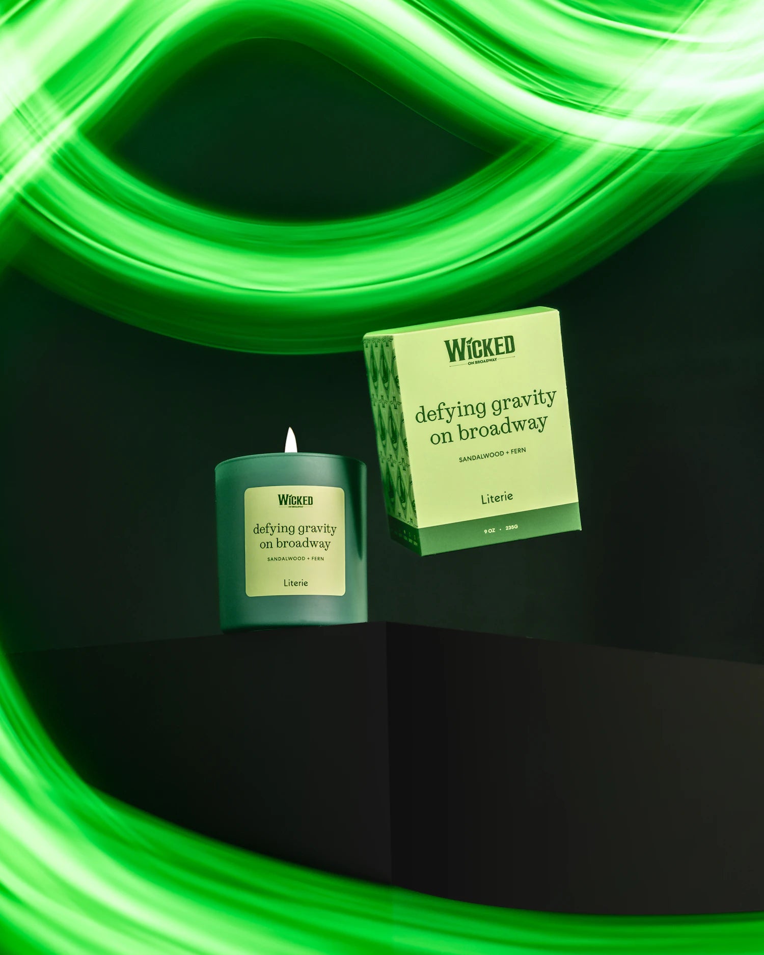 Wicked on Broadway by Literie candle and packaging on a black surface with green lighting.
