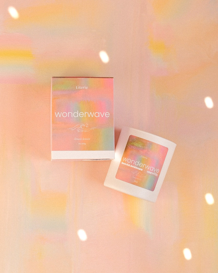 'wonderwave' candle and box on a soft pink background with blurred lights.