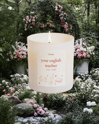 Candle that says your english teacher on it against a floral background.