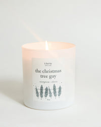 Lit candle with 'the christmas tree guy' label on a white background